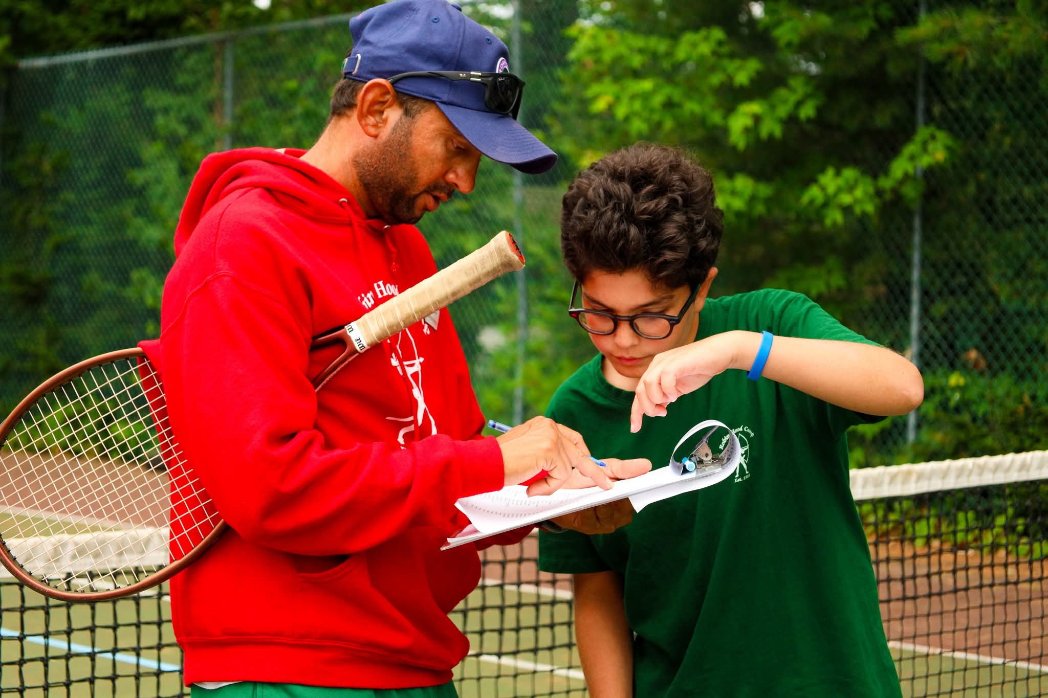 Coach and camper going through notes on court